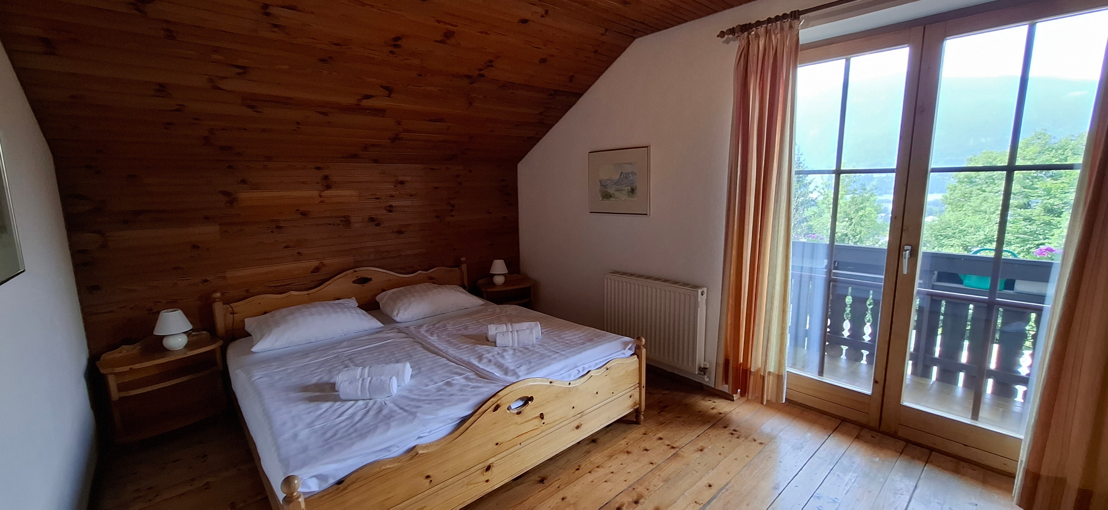 Schlafzimmer mit Doppelbett und Balkon im Obergeschoß