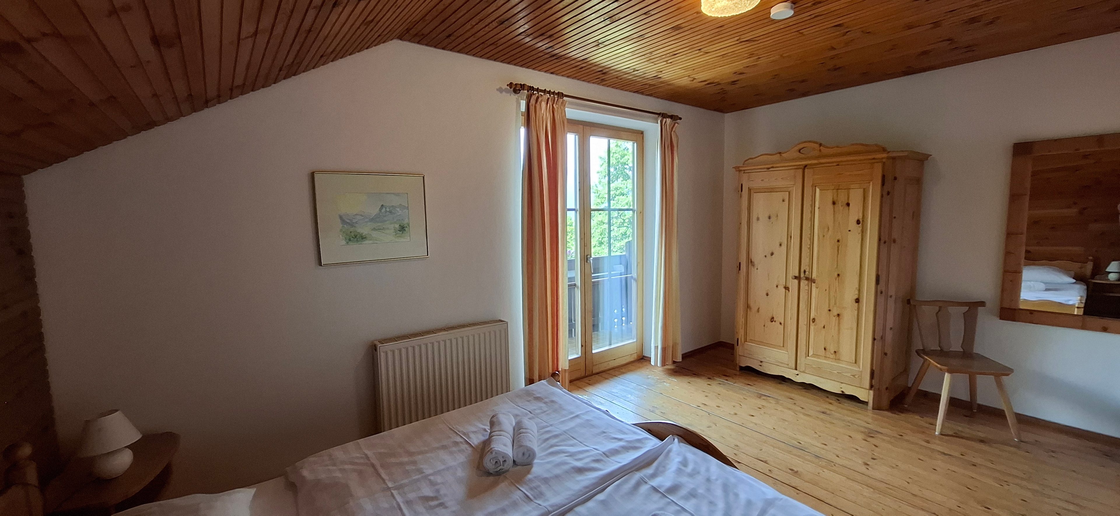 Schlafzimmer mit Doppelbett und Balkon im Obergeschoß