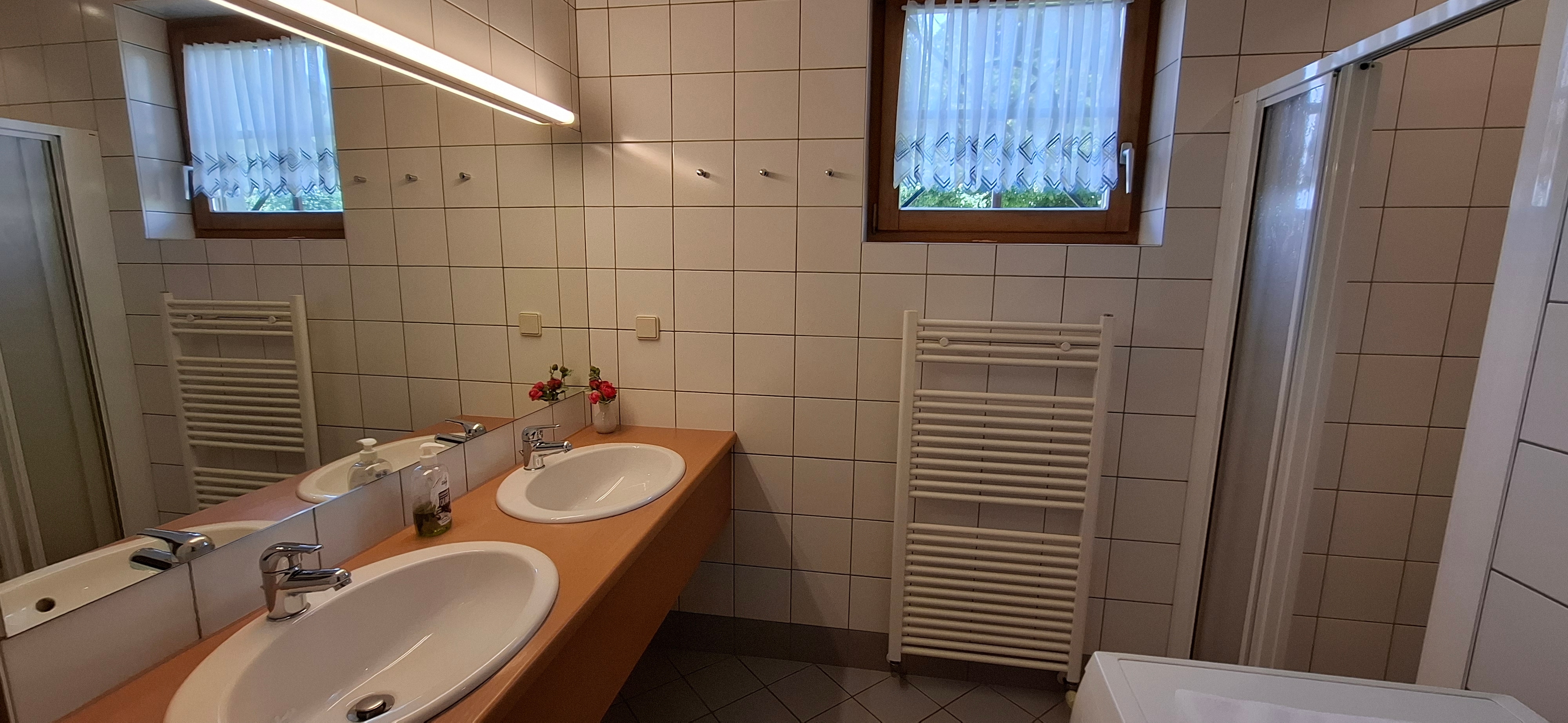 Badezimmer mit Dusche, Doppelwaschbecken und Waschmaschine im Erdgeschoß